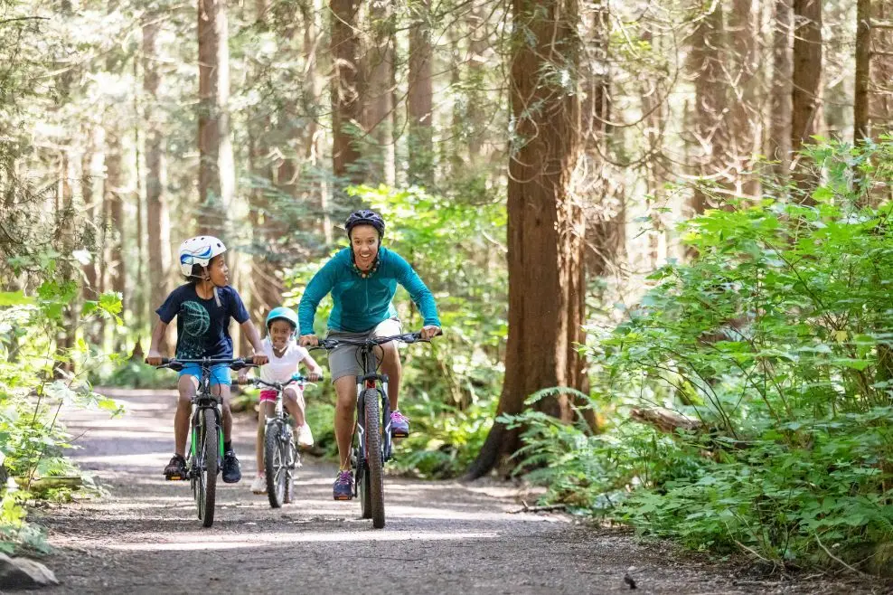 A father and his two children riding bikes on a trail
