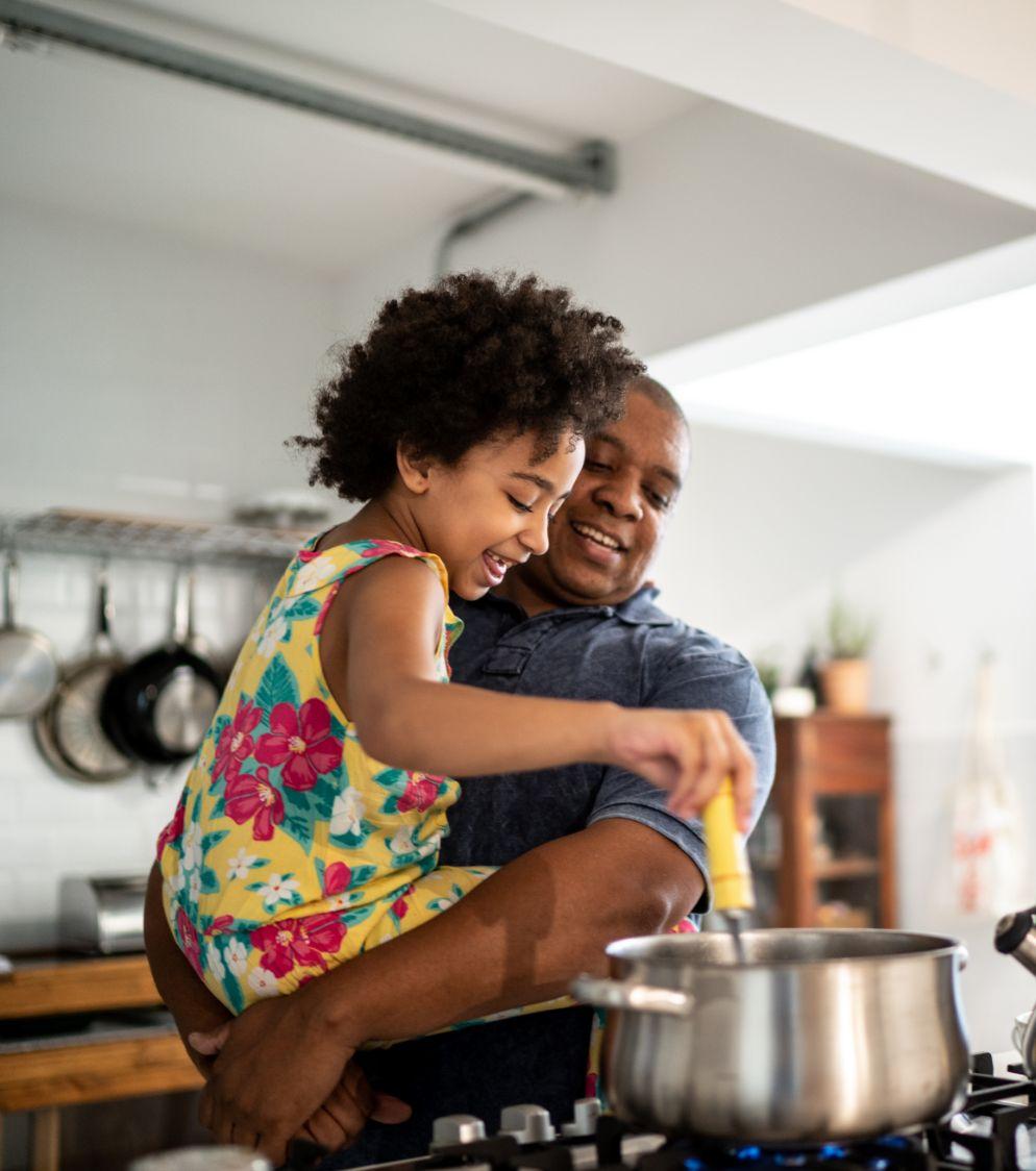 Man cooking a meal in the kitchen with his daughter
